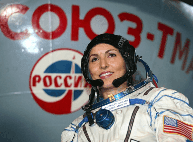 Участница космического полёта Ануше Ансари в скафандре на фоне эмблемы «Союз-ТМА»