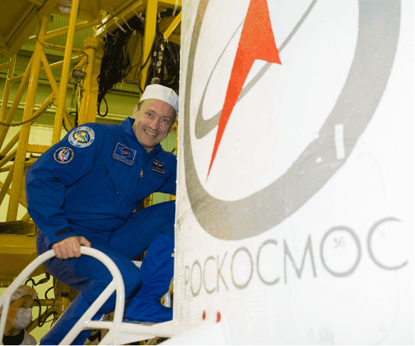 Alexander Misurkin by the rocket fairing with the Roscosmos emblem