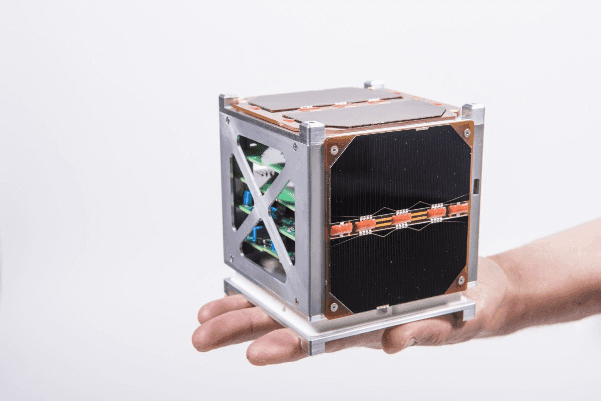 A CubeSat satellite held in the palm of a hand