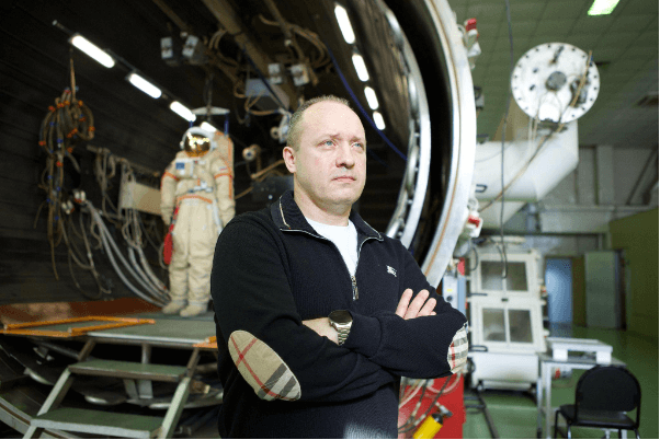 Alexander Misurkin in front of a pressure chamber and a spacewalk suit