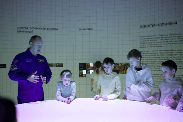 Alexander Misurkin with children at an interactive table at an exhibition