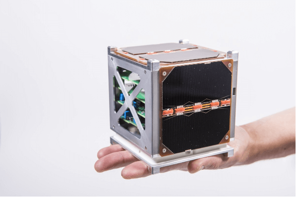 A CubeSat satellite held in the palm of a hand